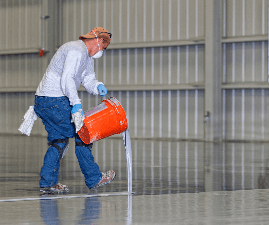 Resin applicator preparing industrial floor in warehouse setting, London
